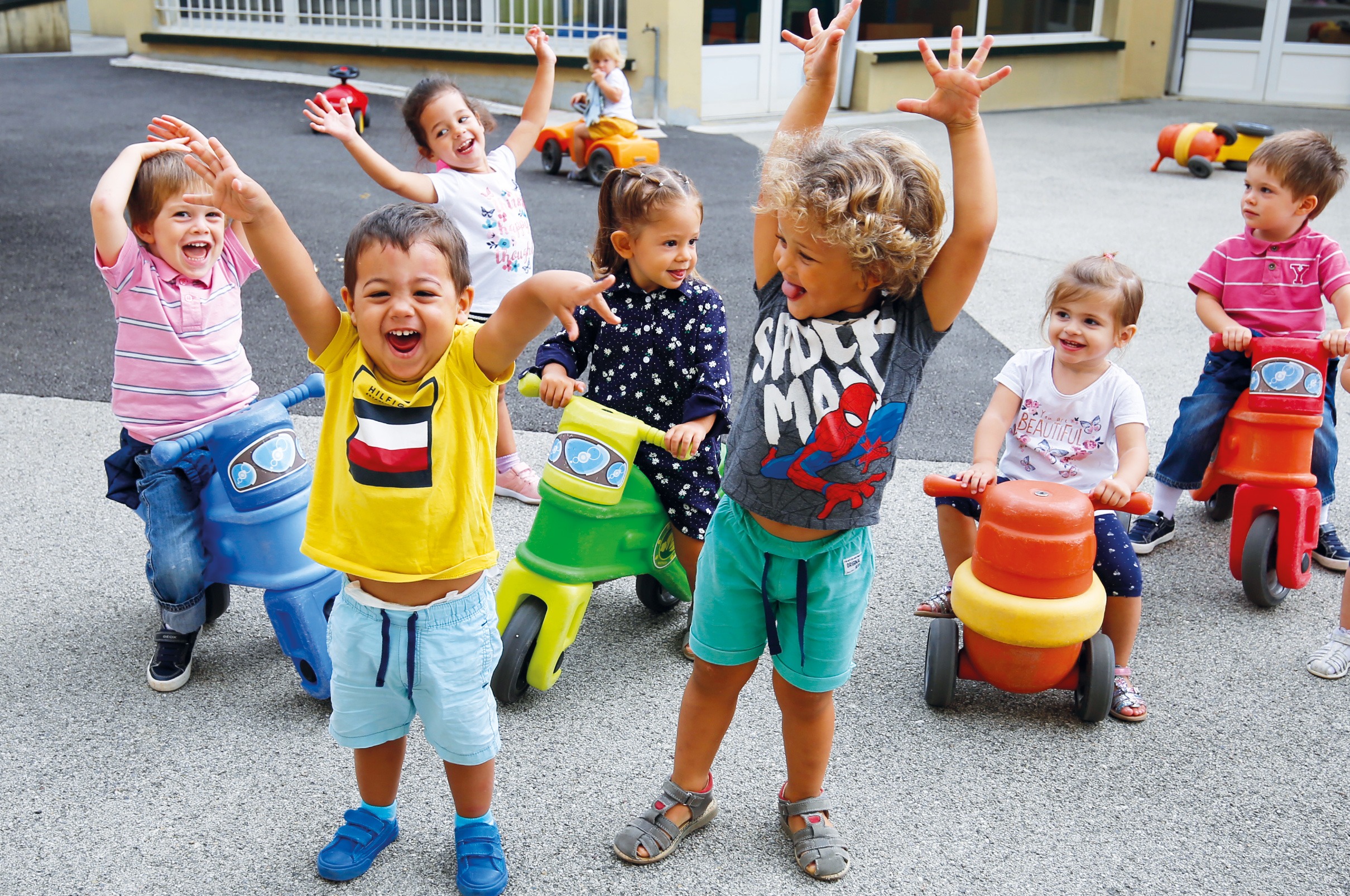 Jeunes enfants jouant sur des porteurs dans la cour d'une crèche