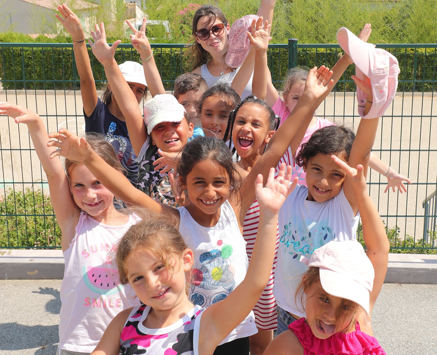 Groupe d'enfants souriants, bras levés, lors d'un accueil de loisirs à Carros