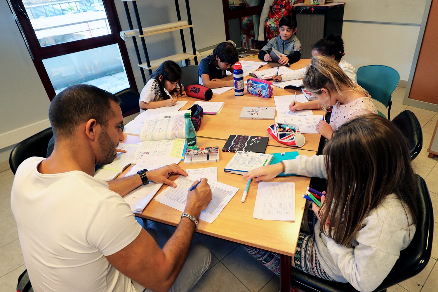 Animateur aidant des enfants à faire leurs devoirs, accompagnement à la scolarité à Carros