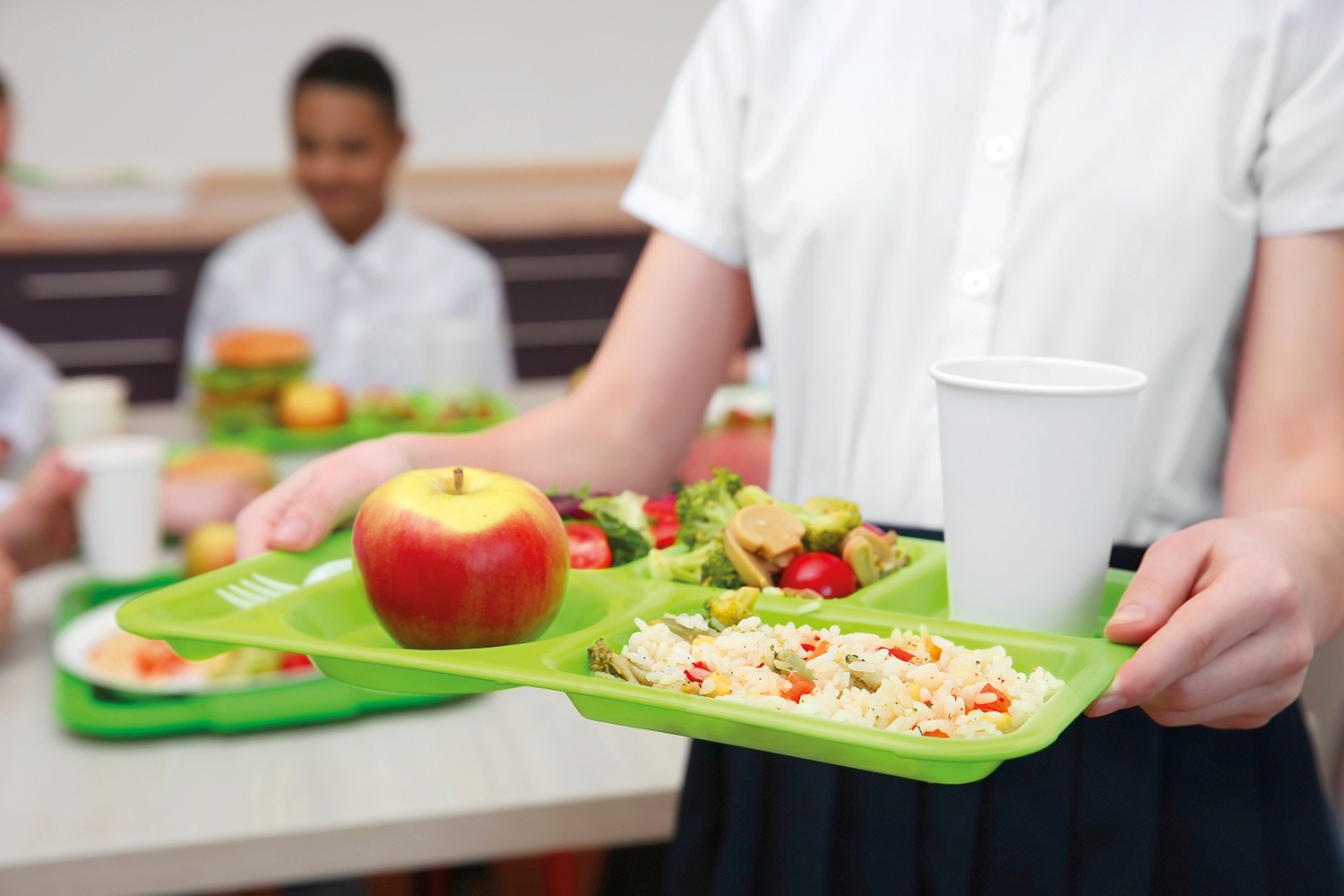 Enfant tenant un plateau-repas à la cantine scolaire