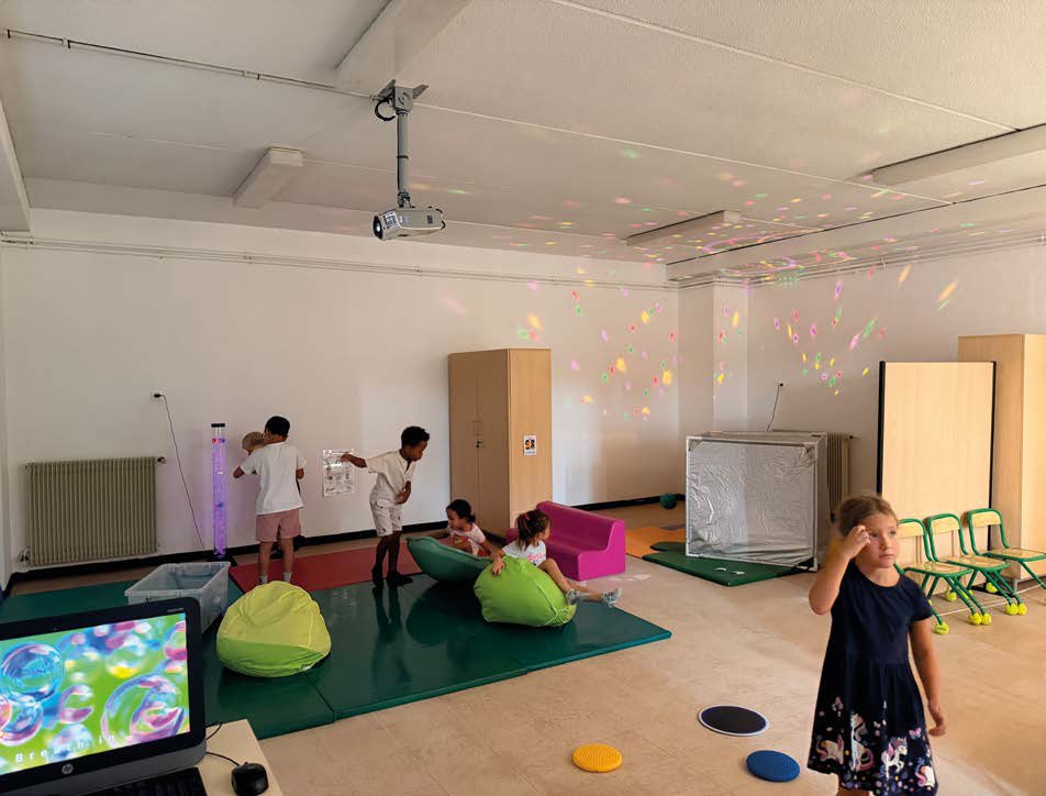 Enfants dans la salle sensorielle de l’école Boris Vian, avec jeux de lumière, poufs et tapis